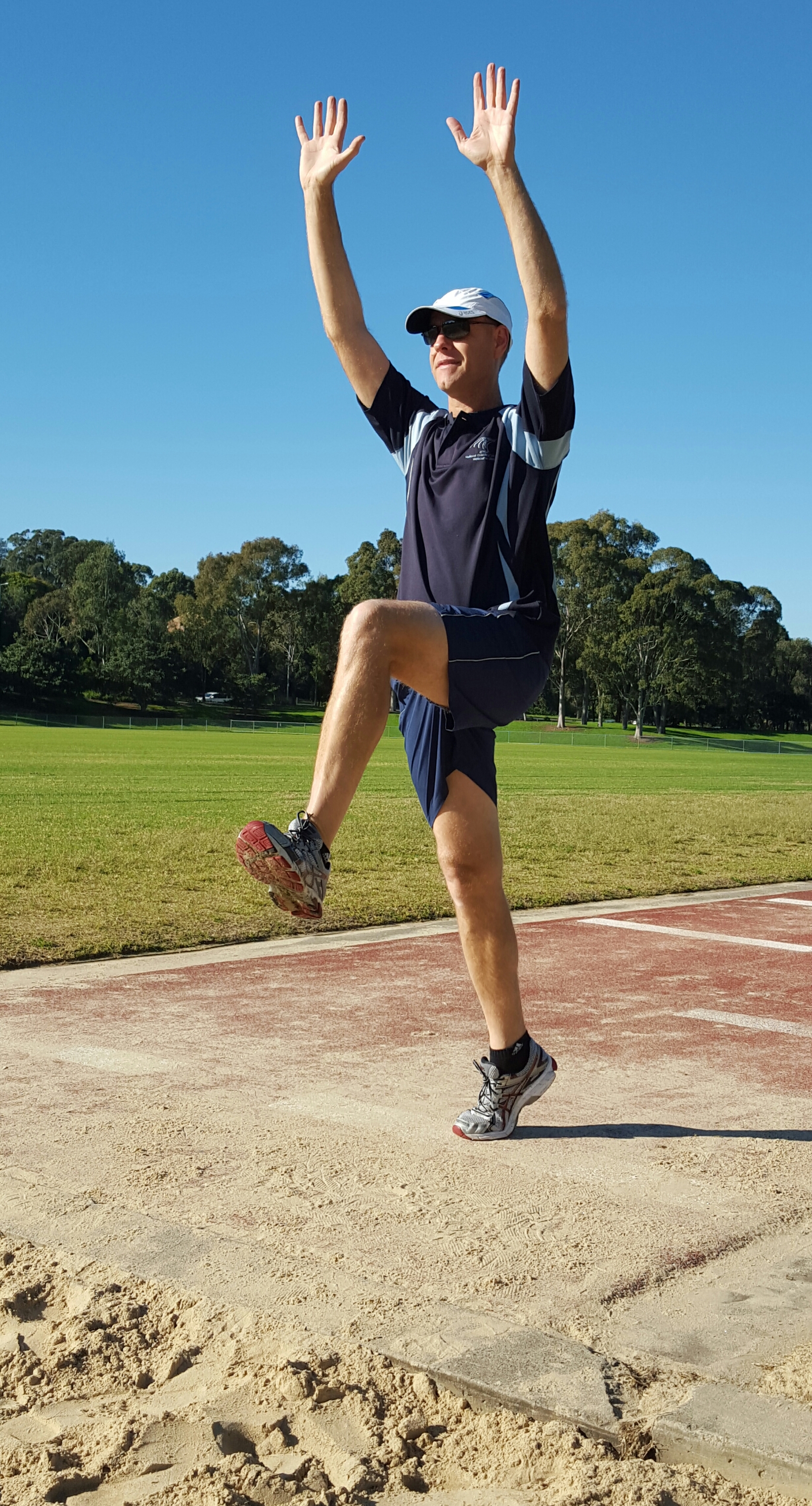 An image demonstrating a long jump take-off position with arms extended above the head.